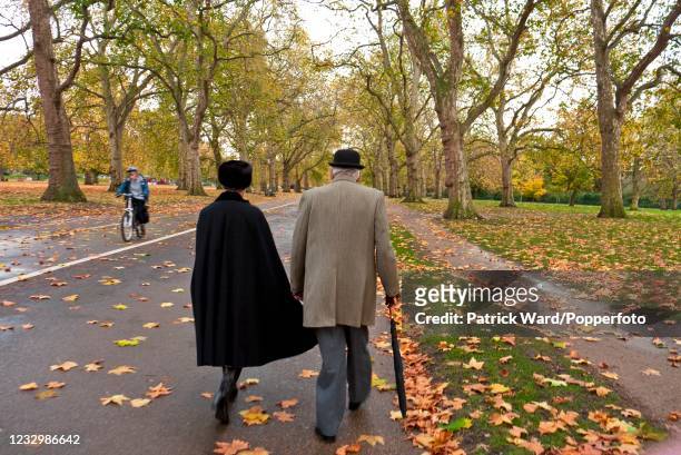 An eldery couple walking through Hyde Park en route to the Remembrance Sunday service at the Royal Artillery Memorial at Hyde Park Corner in London...
