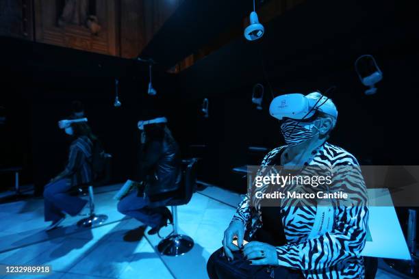 Visitors, with a mask to protect themselves from Covid-19, wear virtual reality glasses, inside the exhibition "Monet: The Immersive Experience", in...