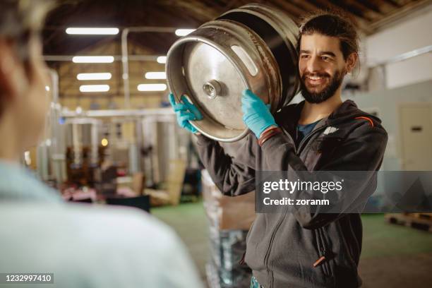 worker carrying beer barrel on shoulder and smiling at manager - keg stock pictures, royalty-free photos & images