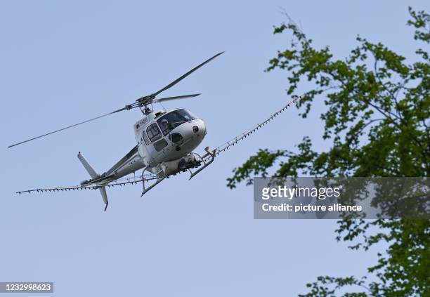 May 2021, Hessen, Frankfurt/Main: A helicopter from the company DHD Heliservice GmbH equipped for spraying operations is on its way to a landing site...