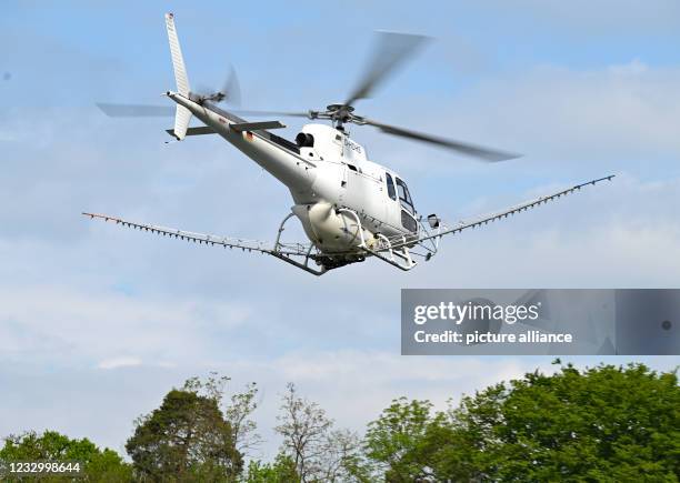 May 2021, Hessen, Frankfurt/Main: A helicopter from DHD Heliservice GmbH, equipped for spraying operations, takes off from the Frankfurt stadium for...