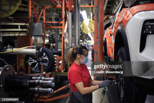 Worker wearing a protective mask installs wheels on a vehicle on the assembly line at the Nissan Motor Co. Manufacturing facility in Smyrna,...