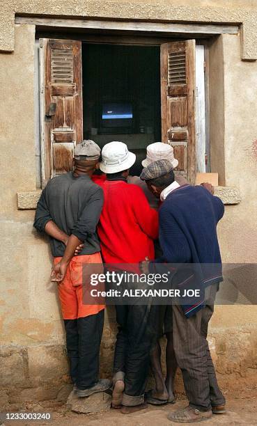 Workers watch the football World Cup 2002 opening match, Senegal vs France, from the window of a house 31 May 2002, in Antananarivo. Most of the...