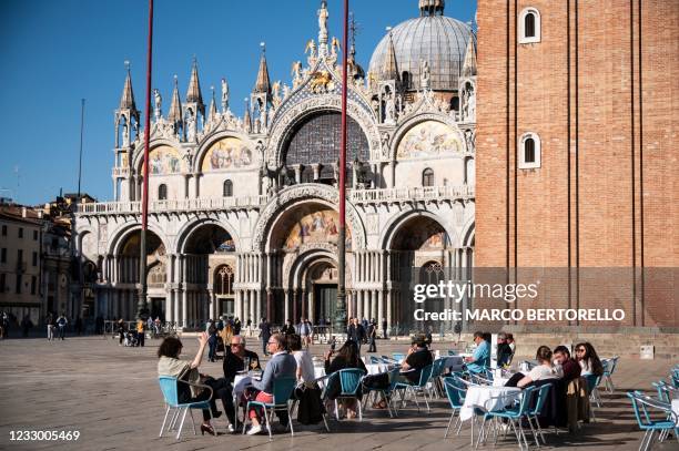 People sit at the terrasse of a cafe in front of the western facade of St Mark's Basilica on Piazza San Marco in Venice on May 20, 2021.