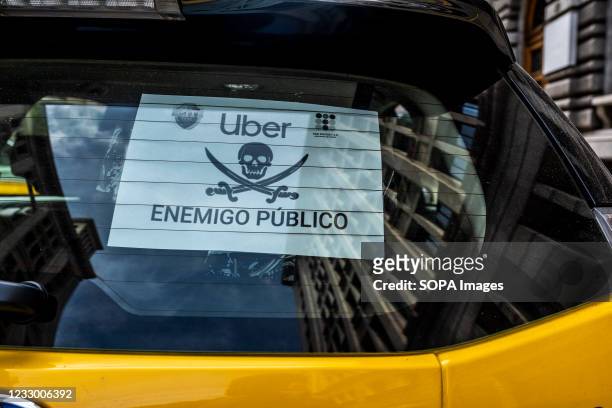 Poster denouncing the company Uber as a public enemy seen on the back of a taxi. Unions and taxi groups have demonstrated with a slow march of...