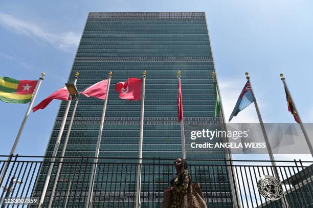 Person walks past flags outside the United Nations headquarters on May 20, 2021 in New York City. - Israel faced an escalating conflict on two fronts...