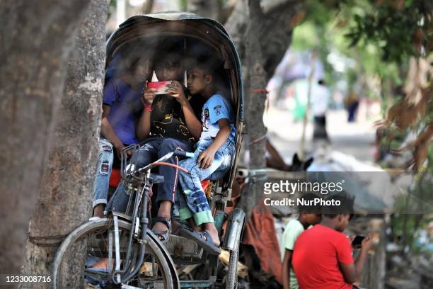 Children play games on smartphones as they sit in a Rickshaw in Dhaka, Bangladesh on May 20, 2021.