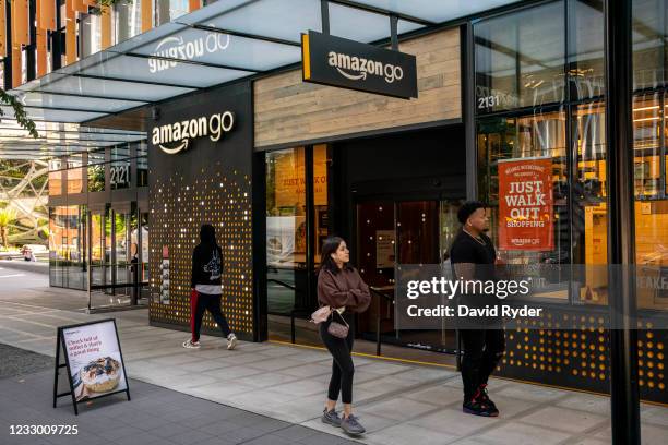 People walk by an Amazon Go store at the Amazon.com Inc. Headquarters on May 20, 2021 in Seattle, Washington. Five women employees sued Amazon this...