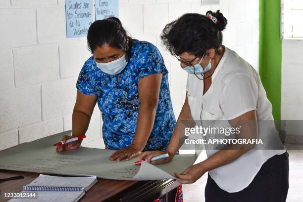 Volunteers from the local community write down information on a piece of cardboard as part of the Doctors Without Borders child health program amid...