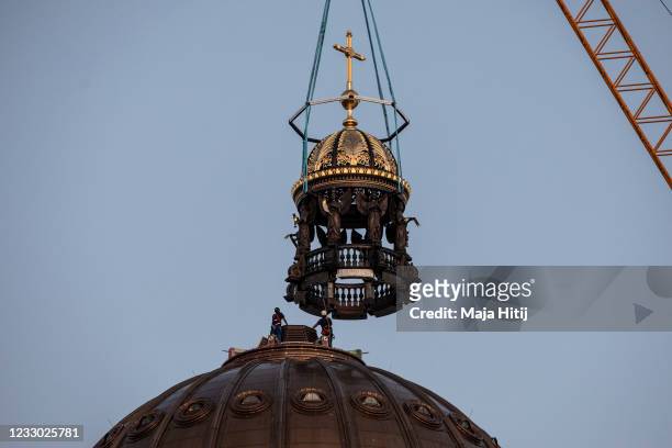 Crane lifts the newly-finished gold-covered cupola and cross onto the dome of the rebuilt Berlin City Palace on May 29, 2020 in Berlin, Germany. The...