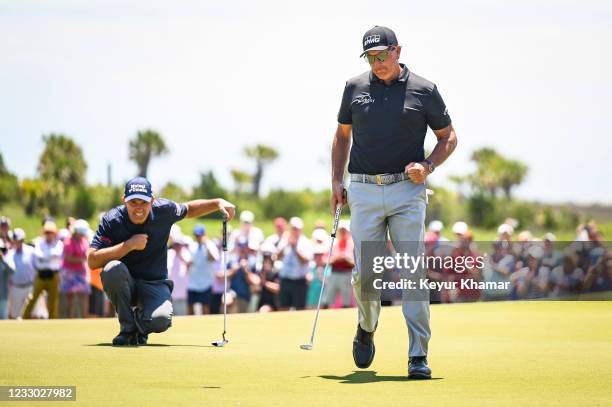 Phil Mickelson celebrates with a fist pump after making a birdie putt on the ninth hole green as Padraig Harrington of Ireland looks on during the...