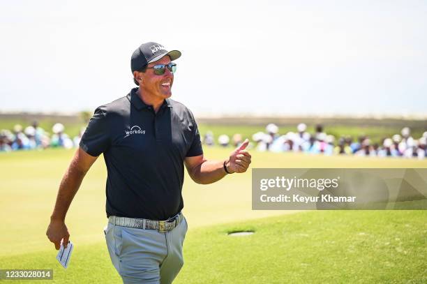 Phil Mickelson smiles and gives a thumbs up to fans after making a birdie putt on the ninth hole green during the second round of the PGA...