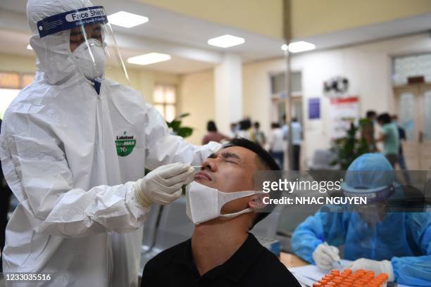 Health worker wearing personal protective equipment conducts a Covid-19 coronavirus swab test on a man at the Center for Disease Control and...