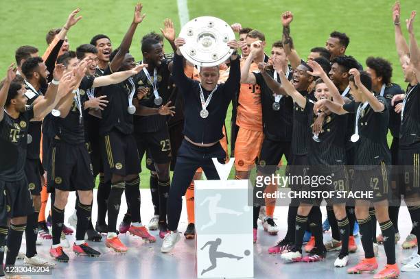 Bayern Munich's German head coach Hans-Dieter Flick and Bayern Munich's team players celebrate with the trophy after the German first division...