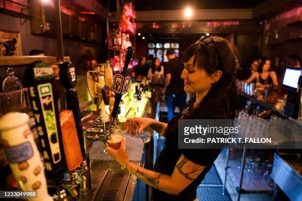 Bartender pours beers for fully vaccinated customers at the bar inside Risky Business, that was once The Other Door but closed during the Covid-19...