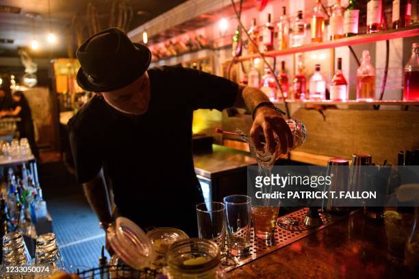 Bartender pours a cocktail for fully vaccinated customers at the bar inside Risky Business, a private members-only club, that was once The Other Door...