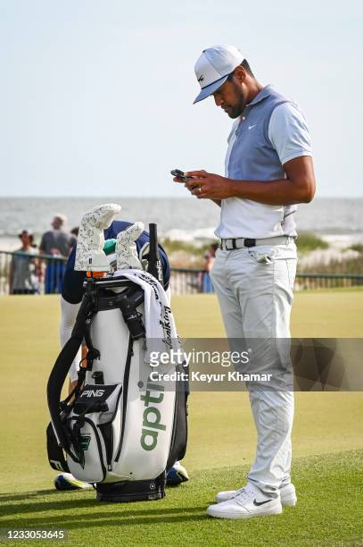 Tony Finau uses his phone next to his bag on the practice green during the third round of the PGA Championship on The Ocean Course at Kiawah Island...