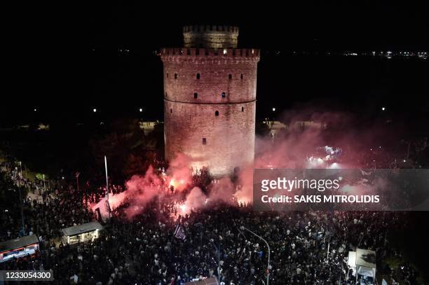 Fans light flares as they celebrate next to the White Tower in Thessaloniki on May 22 after PAOK FC won their Greek Cup Final football match against...