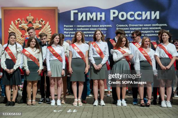 Graduates of the 11th grade of the 12th gymnasium of the city of Tambov at the festive school parade next to the Russian the anthem inscription,...