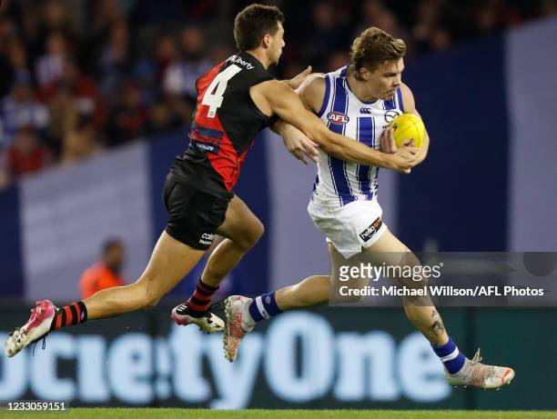 Cameron Zurhaar of the Kangaroos is tackled by Kyle Langford of the Bombers during the 2021 AFL Round 10 match between the Essendon Bombers and the...