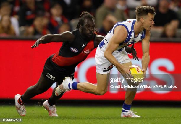 Kayne Turner of the Kangaroos is tackled by Anthony McDonald-Tipungwuti of the Bombers during the 2021 AFL Round 10 match between the Essendon...