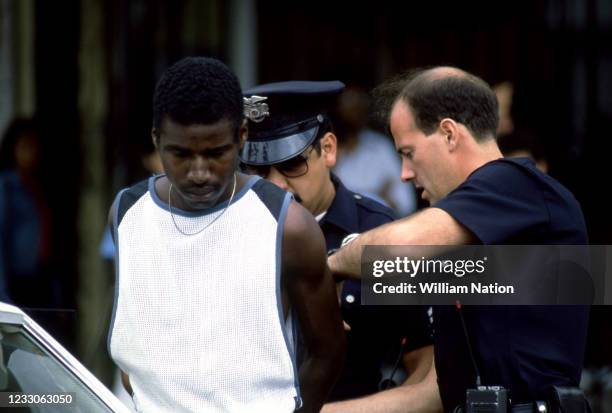 An African-American man is put in handcuffs after being arrested at gunpoint by white Los Angeles police officers in Hollywood, California, circa...