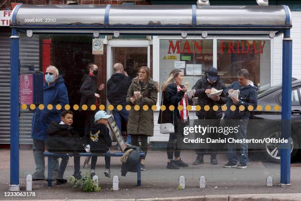 Fans enjoy fish and chips near a bus stop outside he ground before the Premier League match between Sheffield United and Burnley at Bramall Lane on...