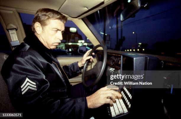 Los Angeles police officer checks his cruiser's computer circa 1988 in Hollywood, California.