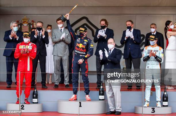 Winner Red Bull's Dutch driver Max Verstappen celebrates with the trophy next to second-placed Ferrari's Spanish driver Carlos Sainz Jr, third-placed...