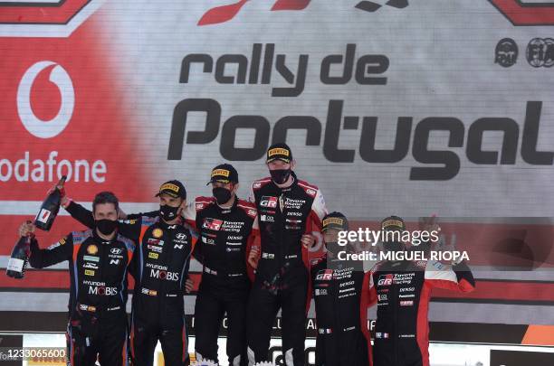 British driver Elfyn Evans and co-driver Scott Martin pose on the podium with Spanish driver Dani Sordo and Spanish co-driver Borja Rozada and French...