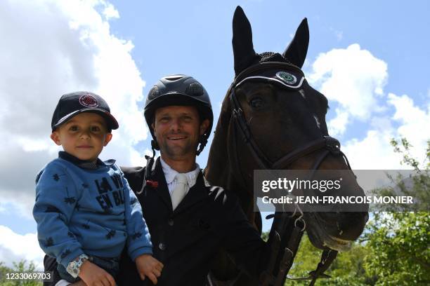 France's rider Nicolas Touzaint, next to his 3-year son, poses with his horse "Absolut Gold HDC", prior to the jumping event of "Le Grand National du...