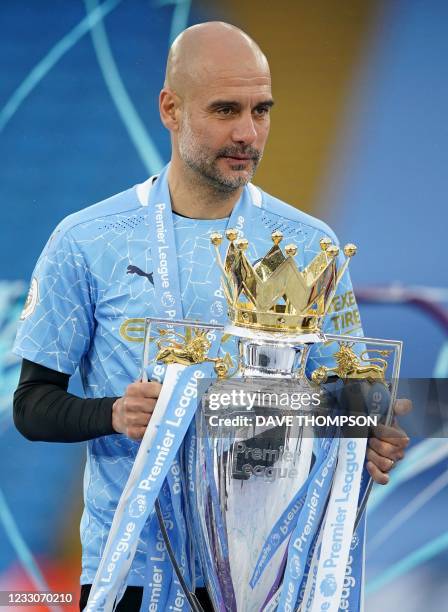 Manchester City's Spanish manager Pep Guardiola holds the Premier League trophy during the award ceremony after the English Premier League football...