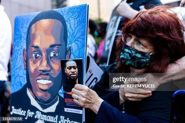 Woman holds portraits of Ahmaud Arbery and George Floyd during an event in remembrance of George Floyd in Minneapolis, Minnesota, on May 23, 2021. -...