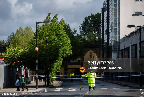 Lollipop lady directs pedestrians next to a police cordon on Consort Road where they are investigating the shooting of Sasha Johnson on May 24, 2021...