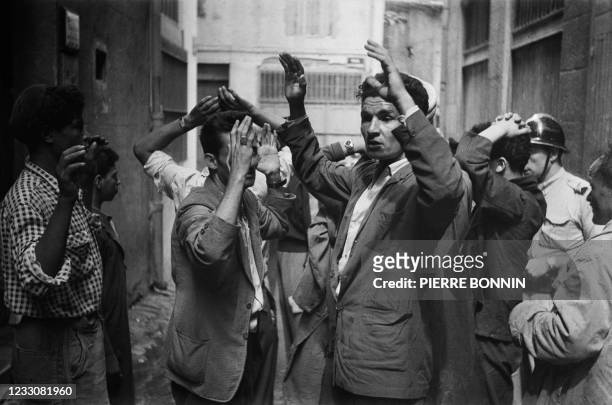 Algerian suspects with hands up are arrested shortly after a car bomb exploded in a street of Constantine on August 24 during the Algerian war, after...