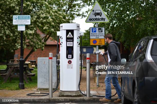 Man charges his vehicle at a recharging point at Maidstone Services on the M20 motorway, south-east of London, on May 24, 2021. - Energy regulator...