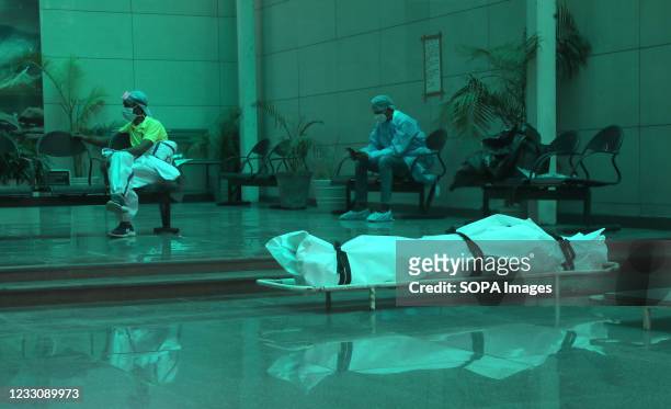 Healthcare worker wearing personal protective equipment sit a distance from a body of a Covid-19 victim before cremation at a crematorium in New...