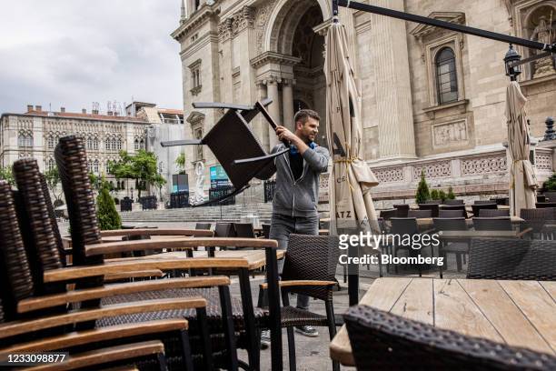 Worker sets out tables and chairs ahead of service on a restaurant terrace outside St. Stephen's Basilica in Budapest, Hungary, on Tuesday, May 25,...