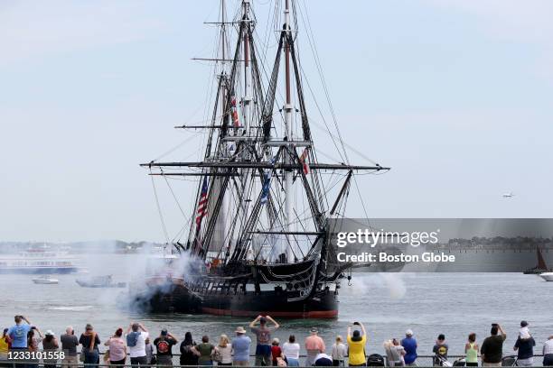 People watch the USS Constitution on its first Boston Harbor outing of the year in Boston on May 21, 2021. The ship was off of Fort Independence...