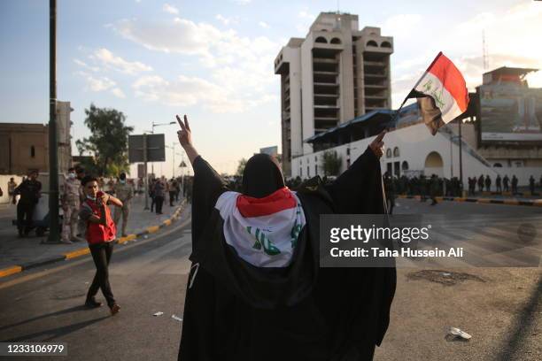 Woman waiving Iraqi flag and trying to stop Riot police after rushing towards protesters on May 25, 2021 in Baghdad, Iraq. Protesters from across the...