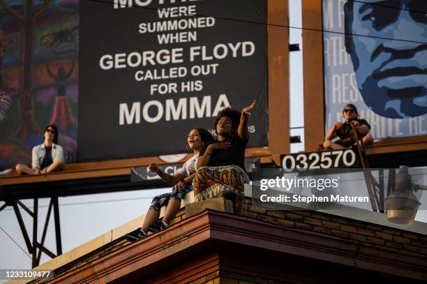 People watch from the roof of a building as musical group Sounds of Blackness perform at George Floyd Square on May 25, 2021 in Minneapolis,...