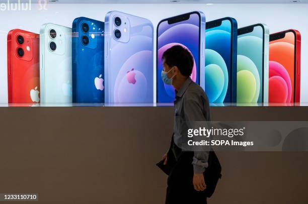 Shopper walks past the American multinational technology company Apple and IPhone 12 and iPhone 12 Pro smartphone commercial outside the store in...