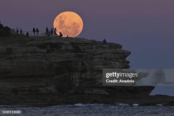 People watch the "Super Flower Blood Moon" rises over the Pacific Ocean at Bondi Beach in Sydney, Australia on May 26, 2021. The "Super" moon...