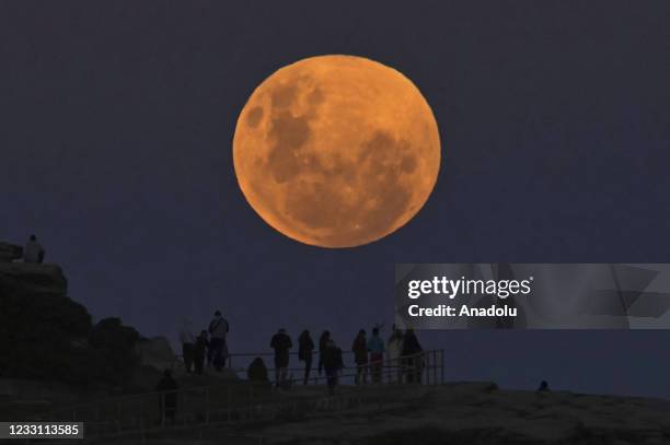 People watch the "Super Flower Blood Moon" rises over the Pacific Ocean at Bondi Beach in Sydney, Australia on May 26, 2021. The "Super" moon...