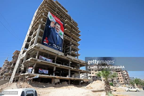 Portraits of Syrian President Bashar al-Assad are hung on buildings at a polling station in Douma, near the capital Damascus on May 26 as voting...