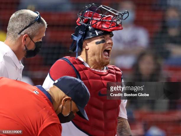 Red Sox catcher Christian Vazquez reacts as he is attended to by a trainer and manager Alex Cora after appearing to injure his arm in the top of the...