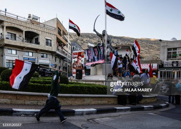 Druze residents of the Israeli-annexed Golan Heights lift Syrian flags during a rally in the village of Majdal Shams, to show support to Syria's...