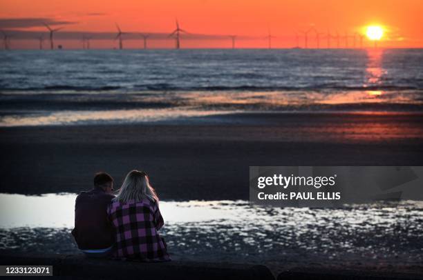 The sun sets behind the Burbo Bank Offshore Wind Farm in Liverpool Bay in the Irish Sea in north west England on May 26, 2021.