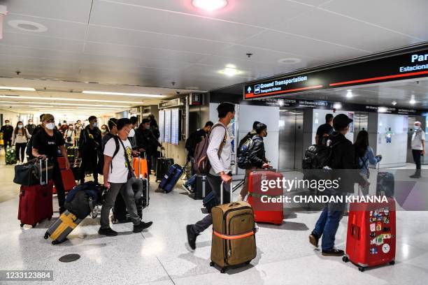 Travelers arrive at Miami International Airport ahead of the long holiday week-end of Memorial Day in Miami on May 26, 2021. - Global air passenger...