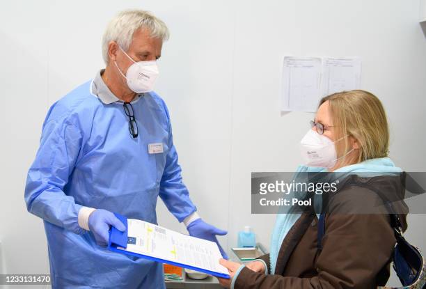 Doctor Christoph Borch shows a woman example of a digital vaccination pass in the Babelsberg vaccination center, after her vaccination against...